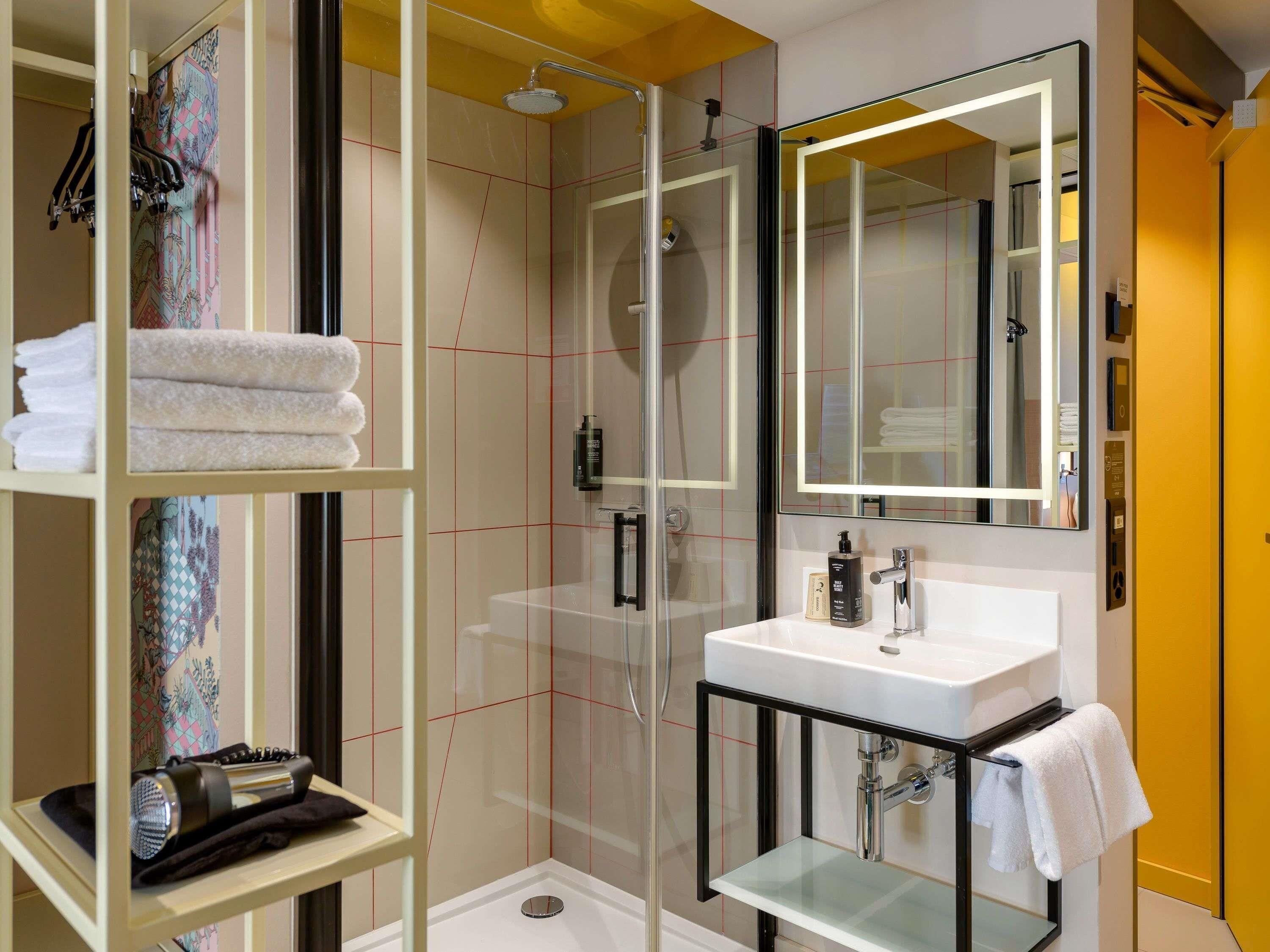 A modern bathroom with a glass shower enclosure, a white sink, and a large mirror.