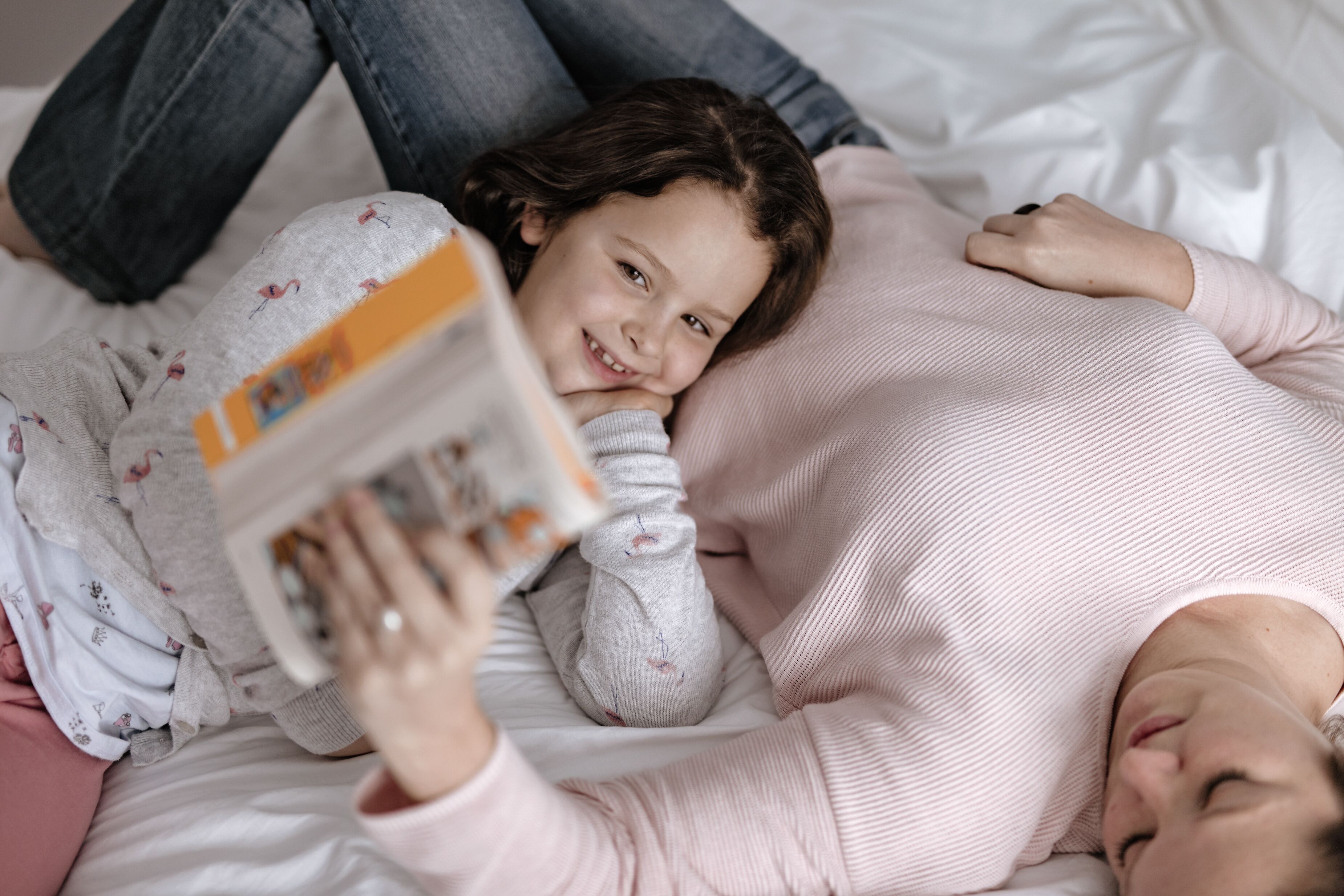 Una persona acostada en una cama leyendo un libro.