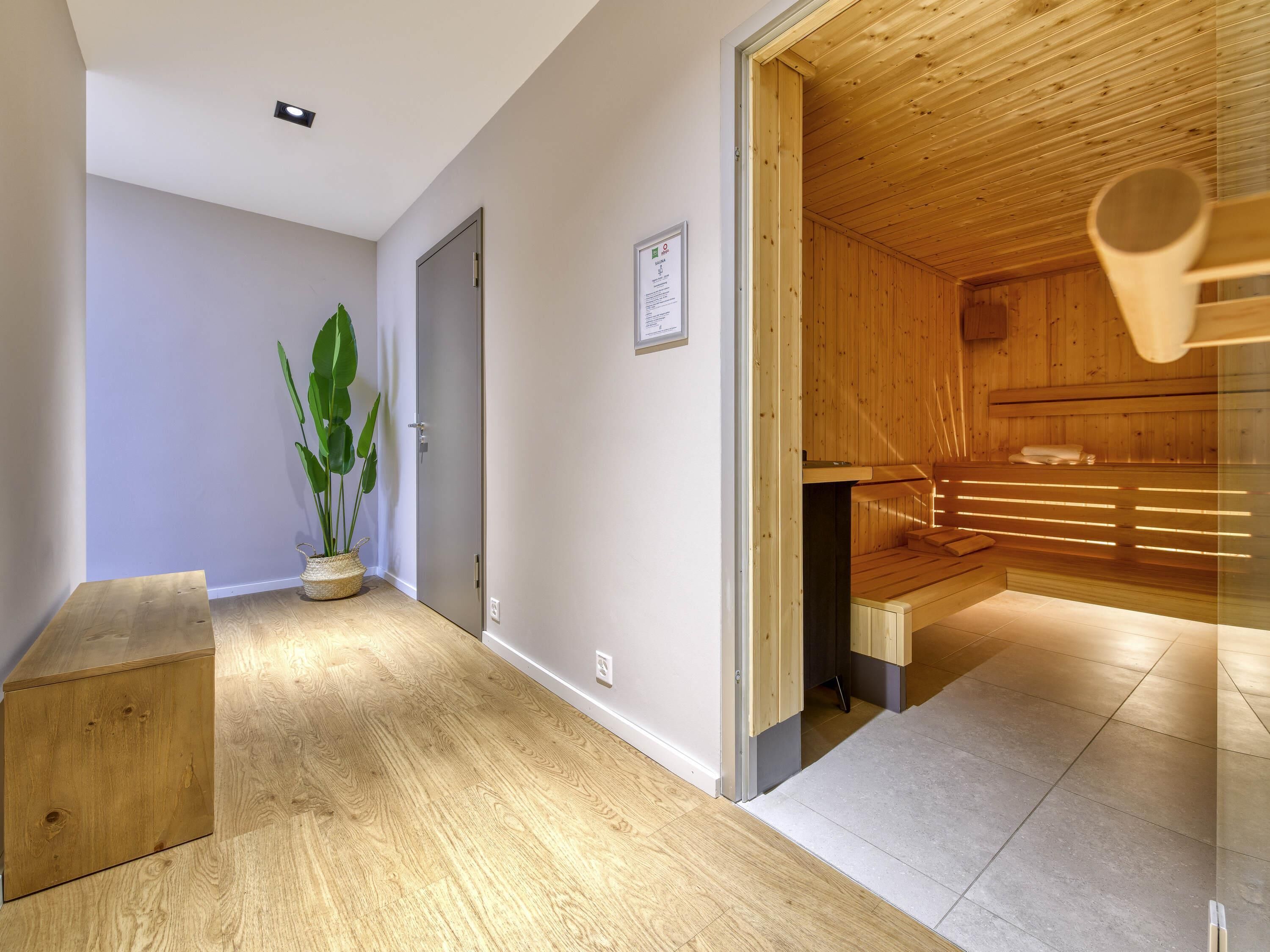 A wooden interior with a bench, a potted plant, and a sauna area.