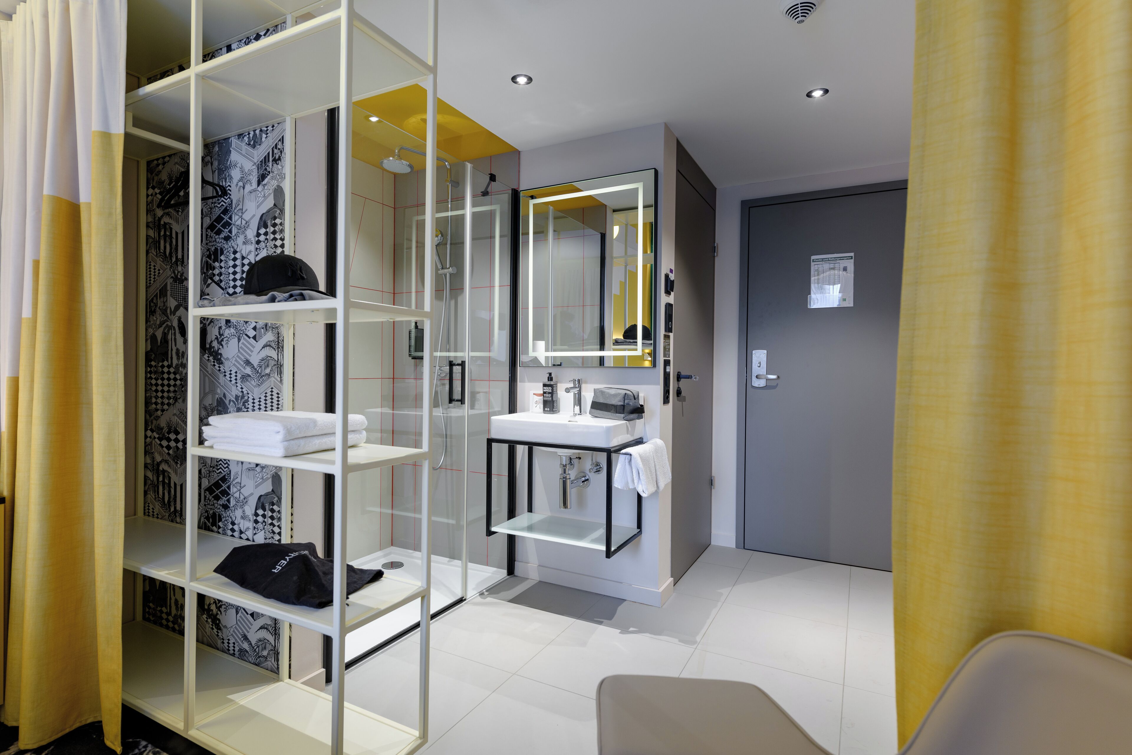 A modern bathroom with a glass shower enclosure, a white sink, and a mirror.