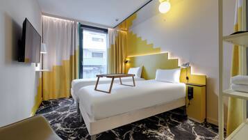 Una habitación de hotel con cama, mesitas de noche, televisión y ventana con cortinas.