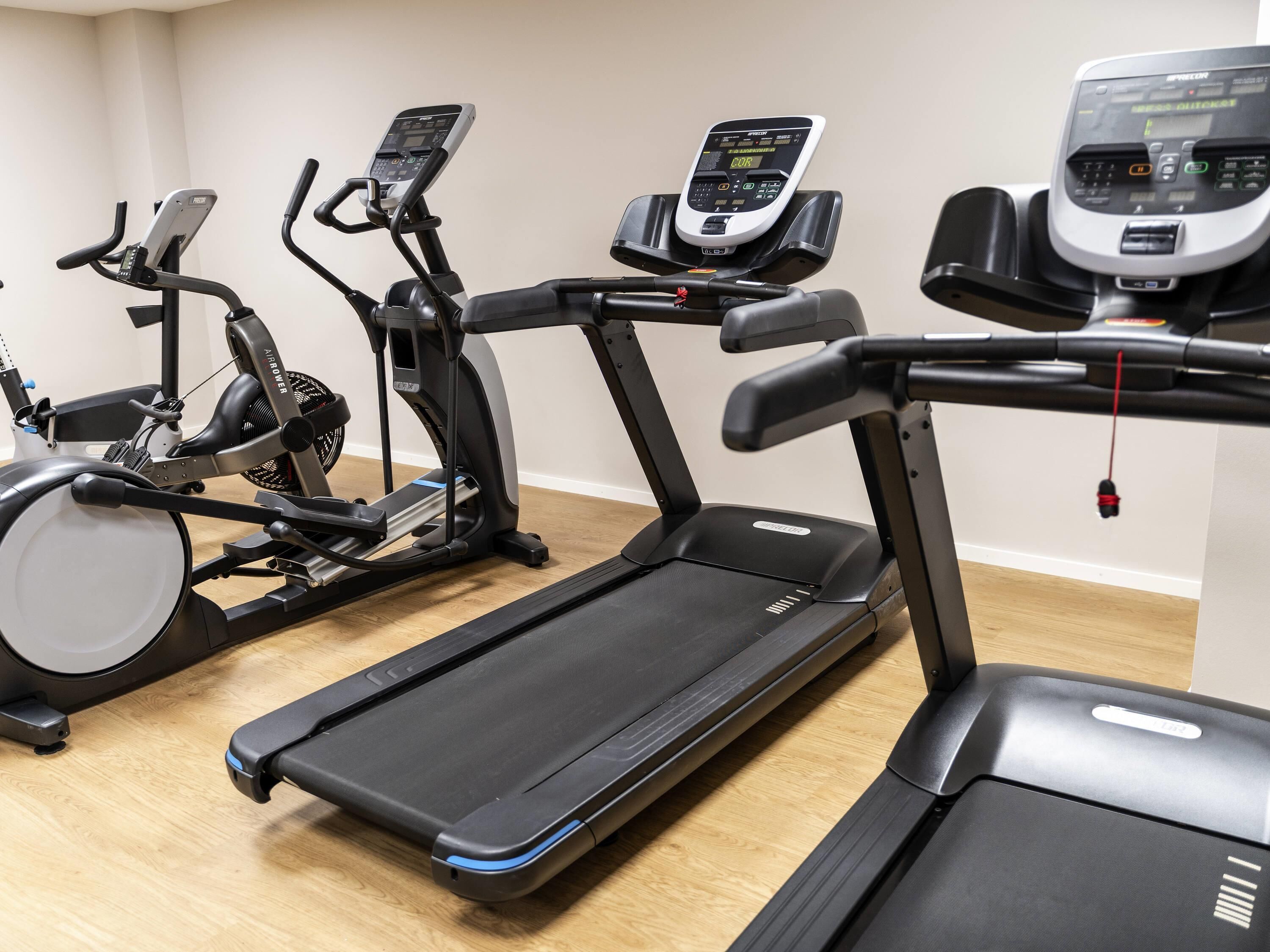 Un gimnasio con bicicletas estáticas, cintas de correr y equipo de ejercicio.