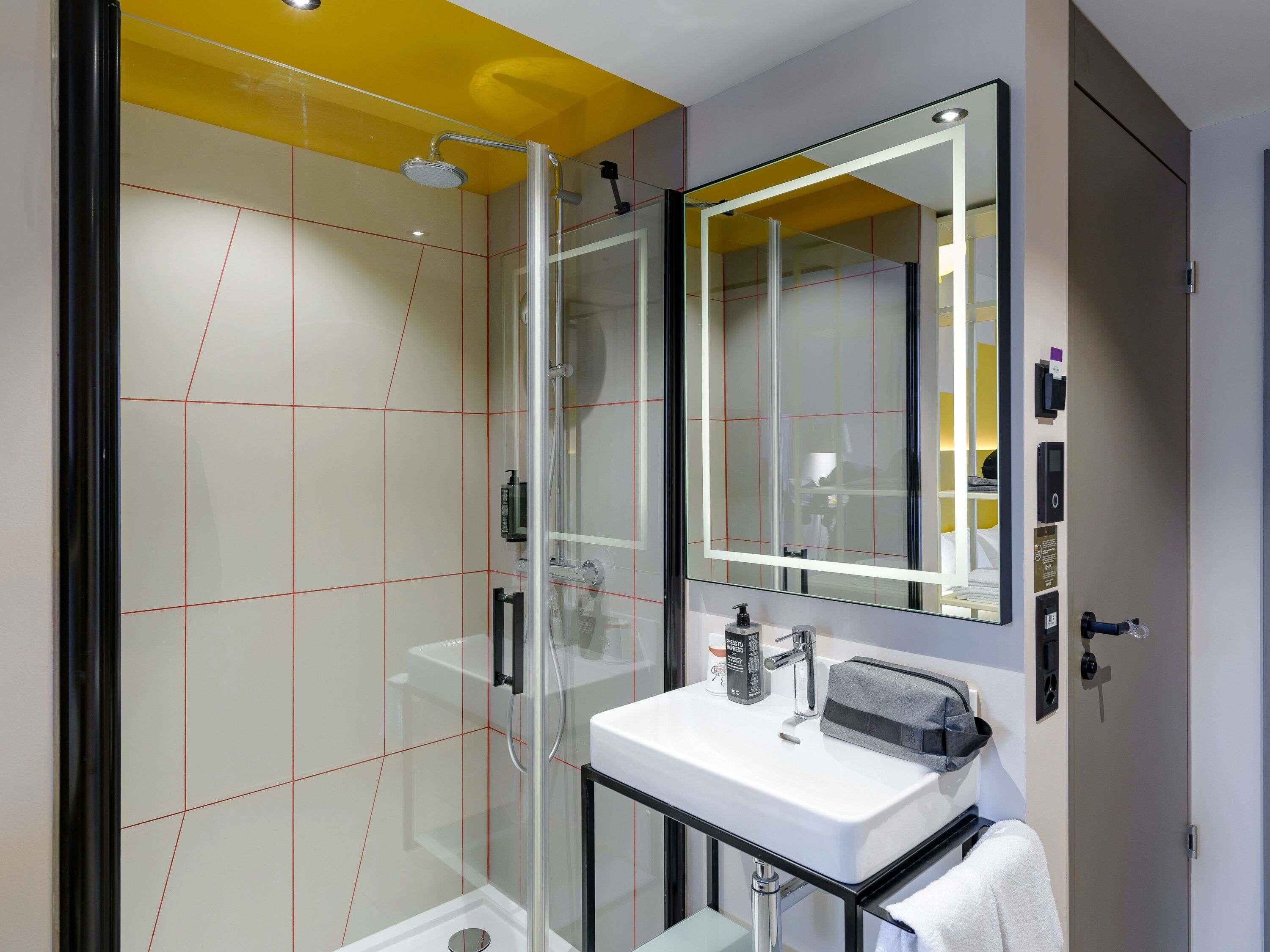 A modern bathroom with a glass shower enclosure, a white sink, and a large mirror.