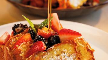 A breakfast plate with French toast, strawberries, blackberries, and a fried egg.