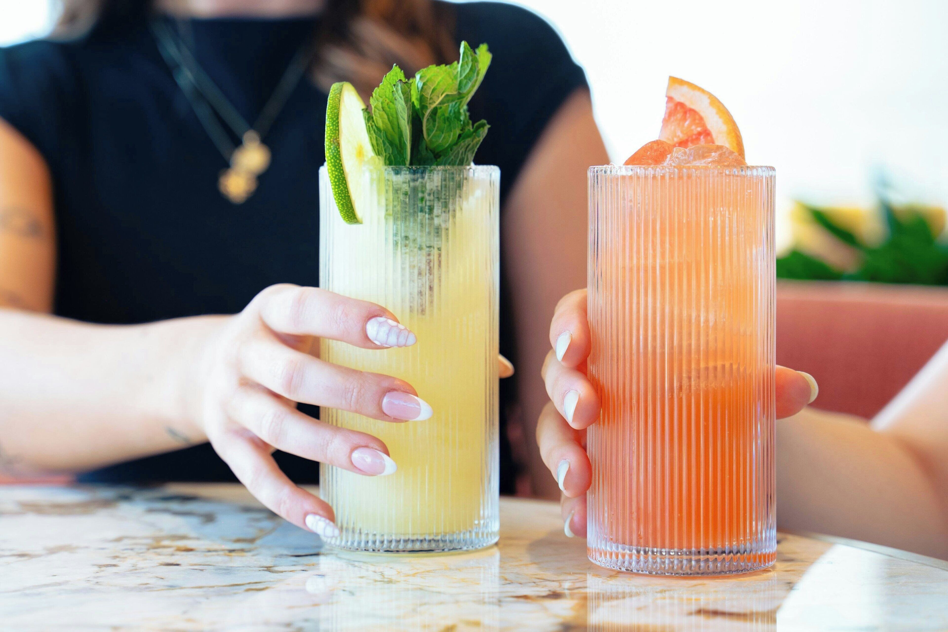 Two drinks with garnishes on a table.
