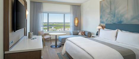 A hotel room with a bed, a desk, a TV, a window with a view, and a sofa.