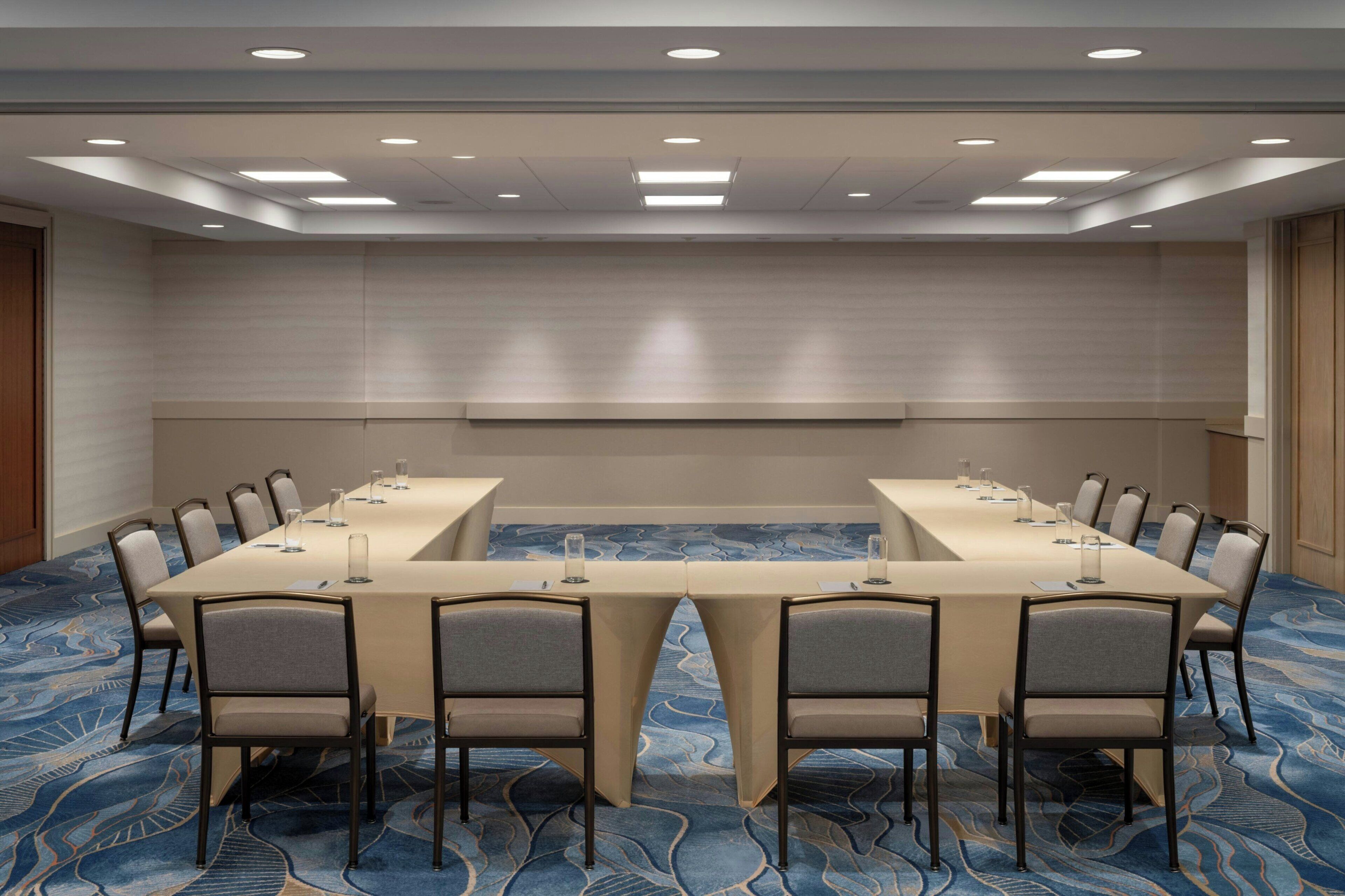 A conference room with a long table, chairs, and a patterned carpet.
