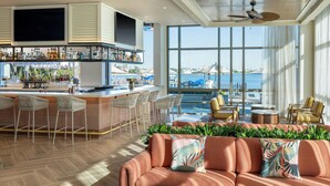 A bar area with a TV, bar stools, and a view of the sea.