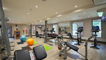 A gym with various exercise equipment, including treadmills, weight machines, and exercise balls.
