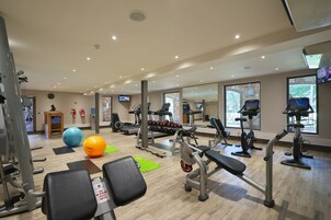 A gym with various exercise equipment, including treadmills, weight machines, and exercise balls.