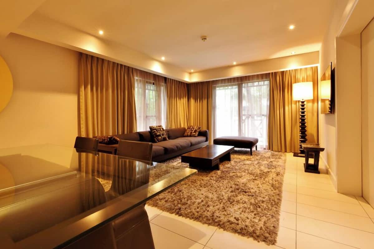 A modern living room with a sofa, ottoman, coffee table, and a glass-top table.
