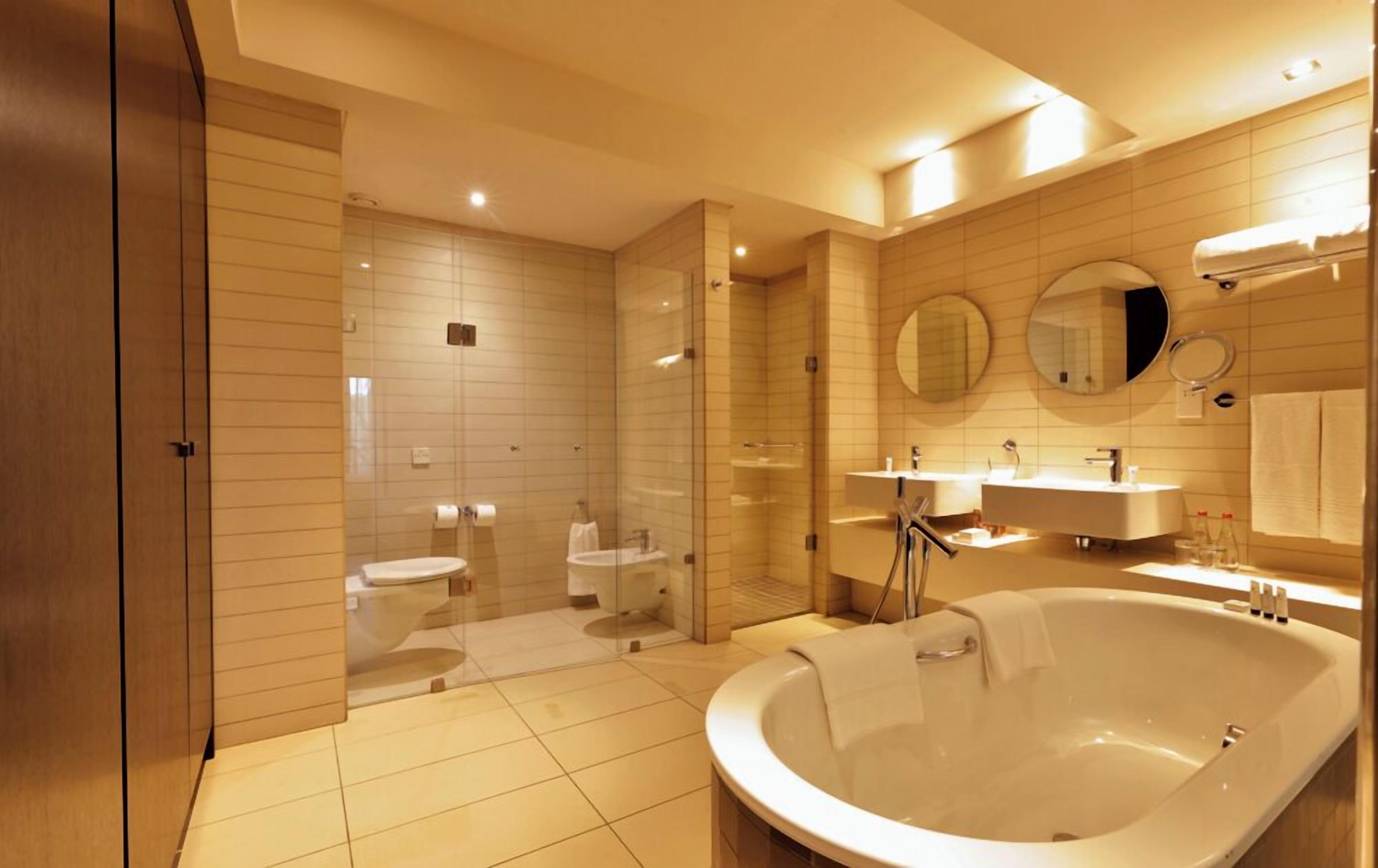 Une salle de bain moderne avec une grande baignoire, deux lavabos, une douche à l’italienne et des toilettes.