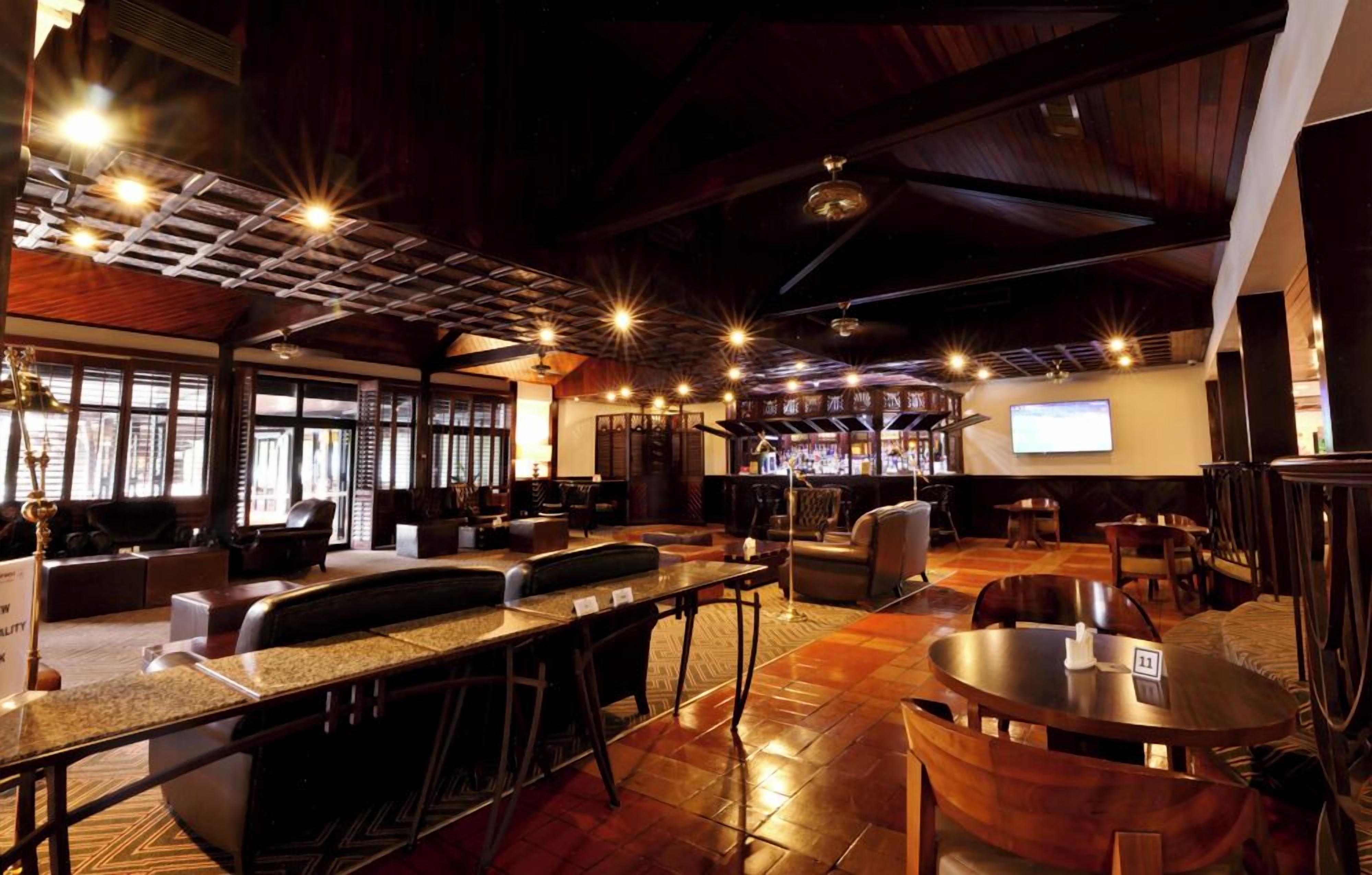 Ein großzügiger Lounge-Bereich mit verschiedenen Sitzgelegenheiten, darunter Sofas und Tische, sowie ein Barbereich mit Fernseher.