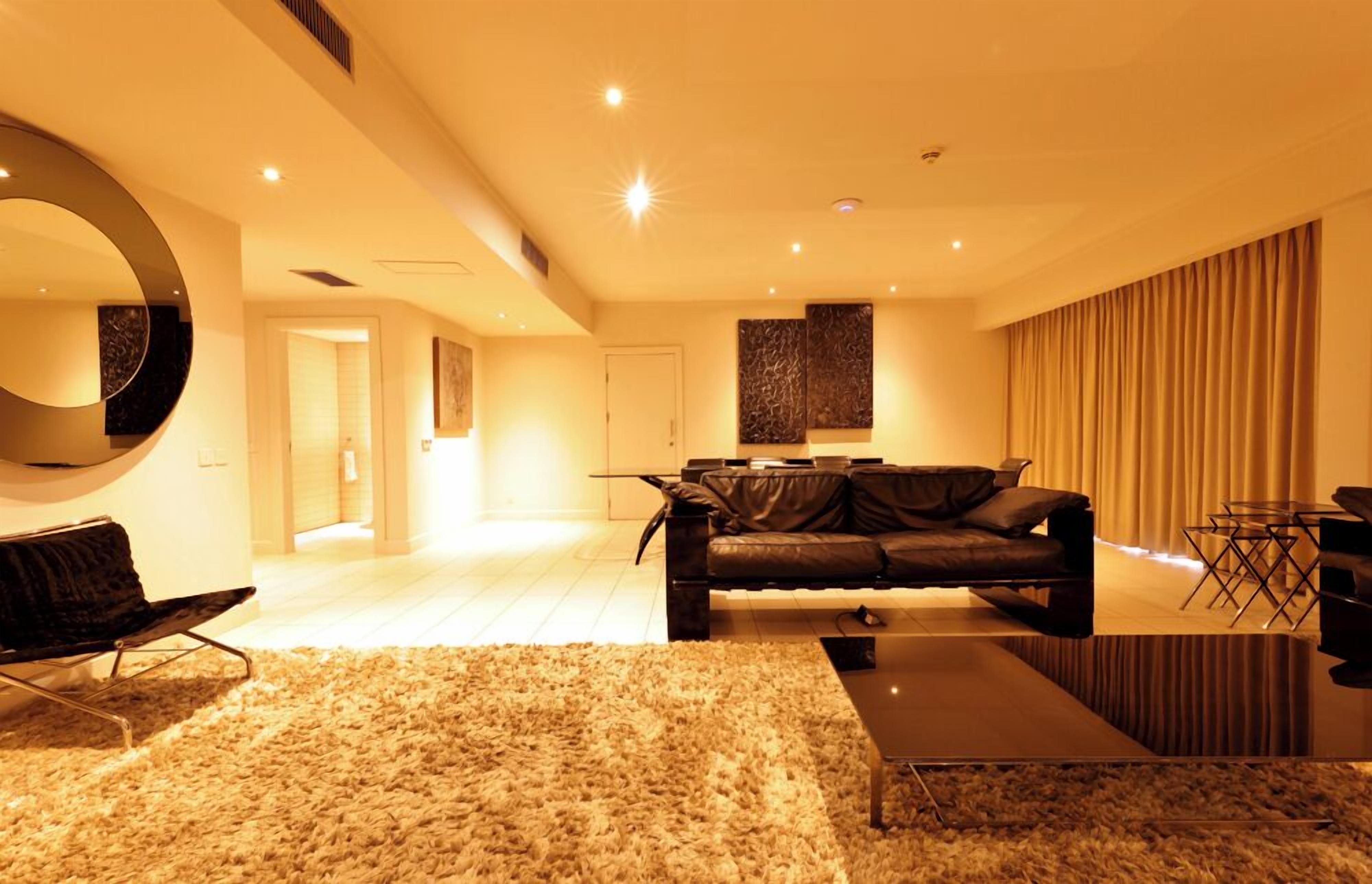 Een moderne woonkamer met een leren bank, een ronde spiegel en een bijzettafeltje.