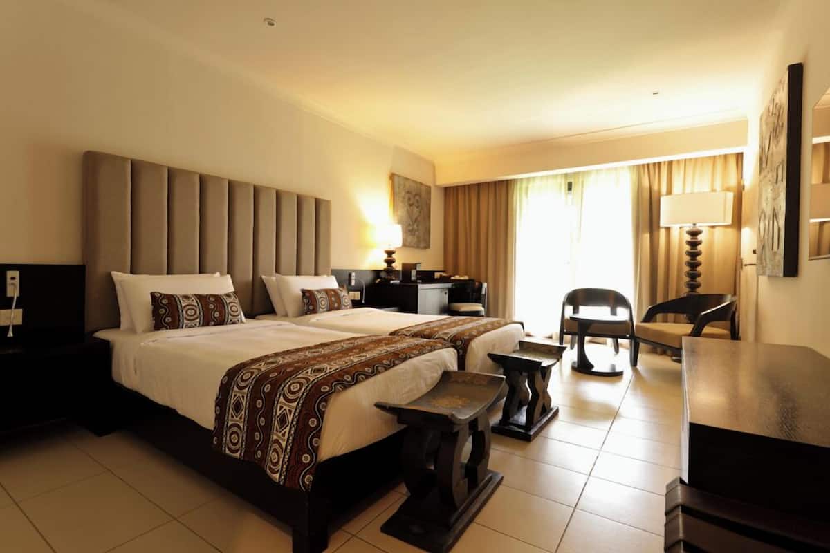 A hotel room with a large bed, a desk, a chair, and a lamp.
