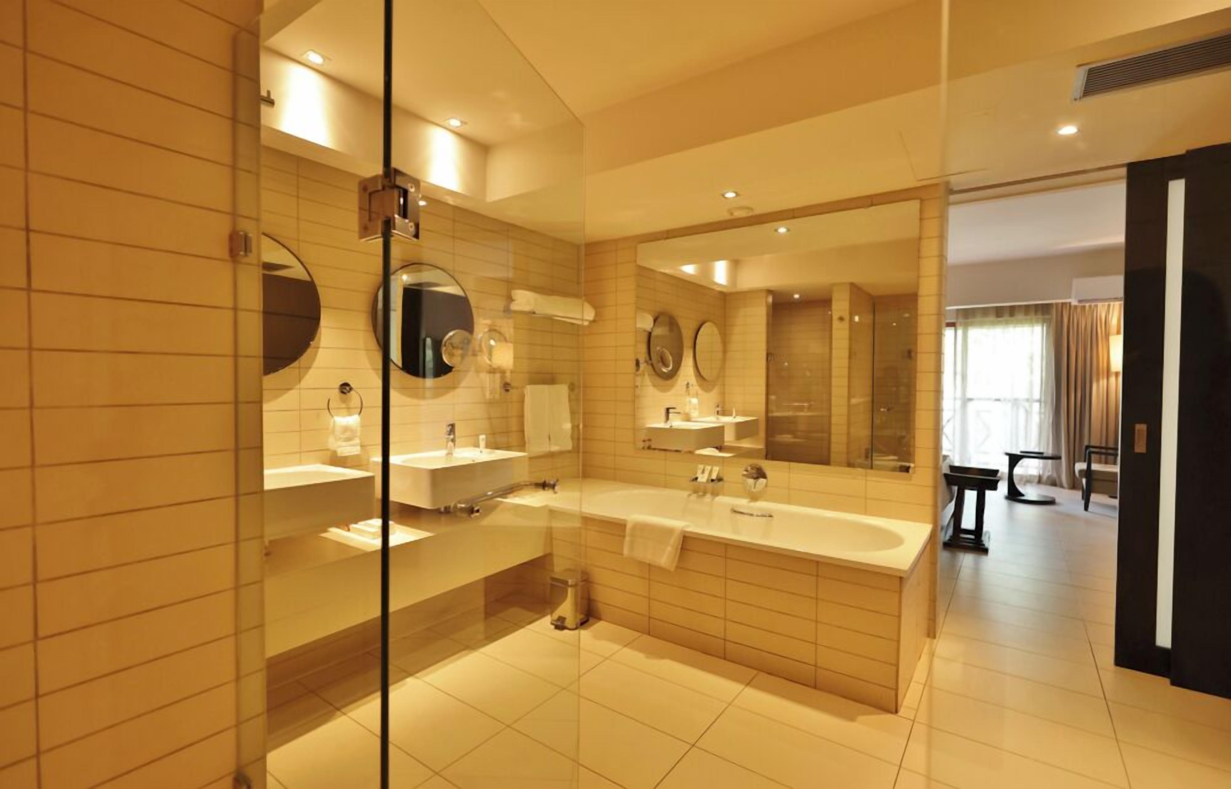 Un baño moderno con un espejo grande, dos lavamanos, una bañera y una cabina de ducha de vidrio.