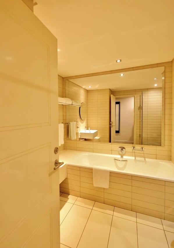 A modern bathroom with a large bathtub, a sink, and a mirror.