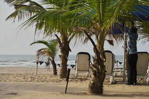 Una playa cerca, arena blanca, sillas reclinables de playa, sombrillas