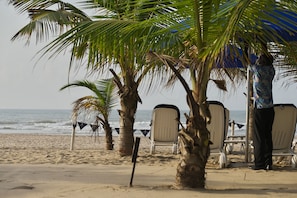 Una playa cerca, arena blanca, sillas reclinables de playa, sombrillas