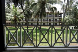 A hotel with a balcony, palm trees, and a well-maintained lawn.