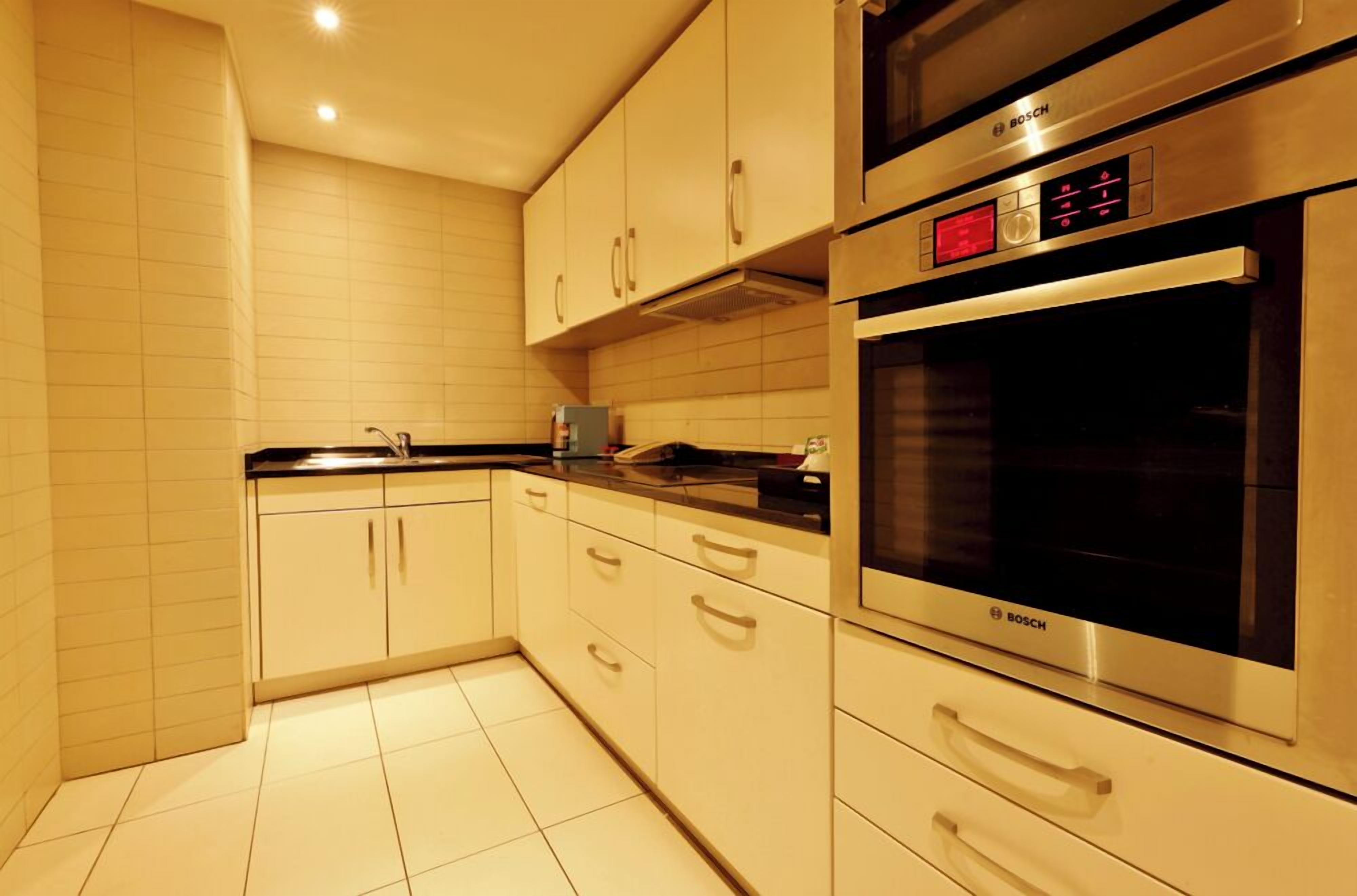 A modern kitchen with white cabinets, a Bosch oven, and a microwave.