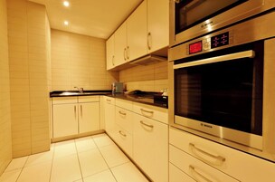 A modern kitchen with white cabinets, a Bosch oven, and a microwave.
