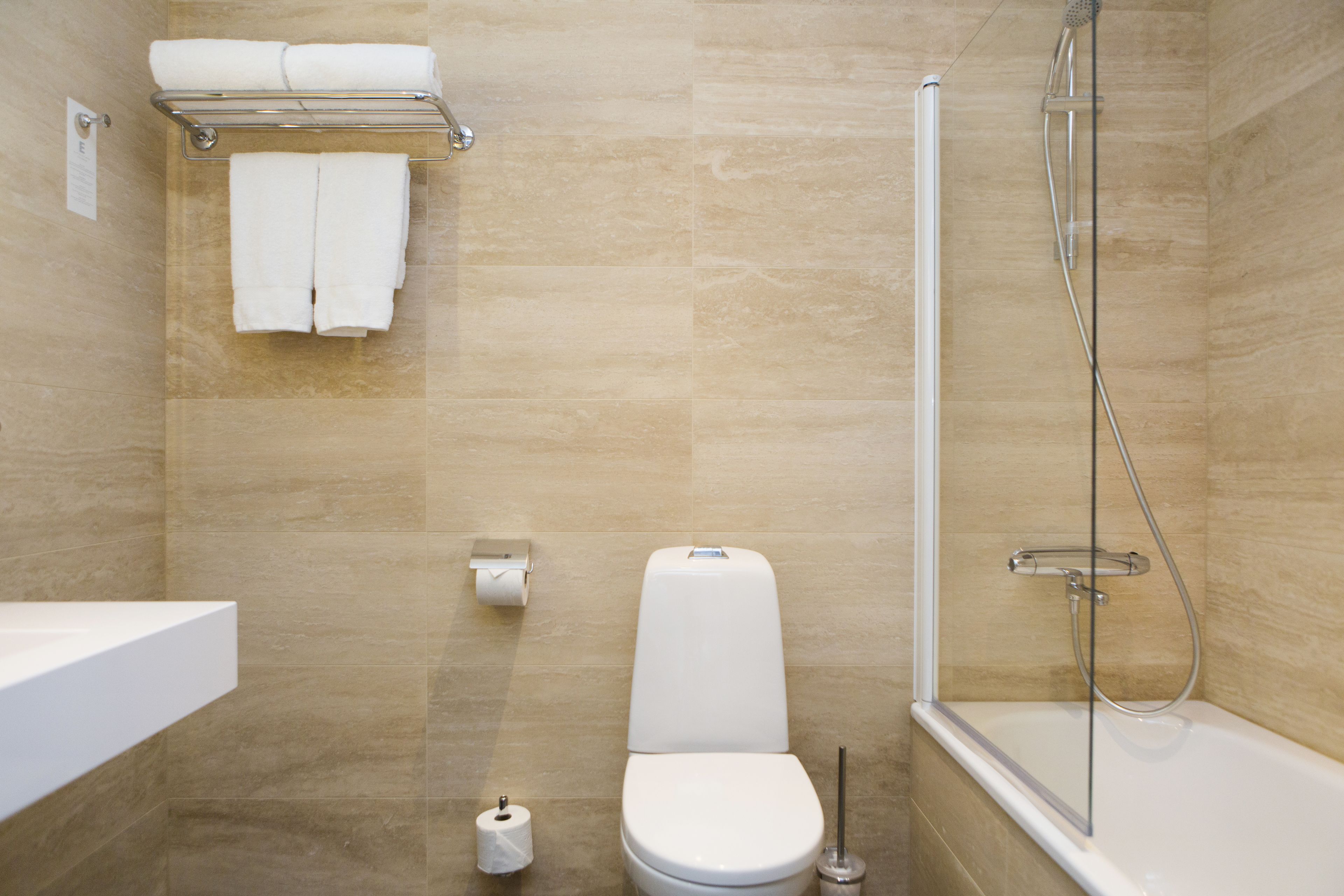 Une salle de bain comprenant des toilettes, un lavabo, une douche et un porte-serviettes.