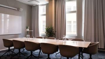 Una sala conferenze con una lavagna, un tavolo lungo e sei sedie.