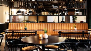 A restaurant interior with round tables, black chairs, and a wooden bench. - Elite Palace Hotel & Spa (Stockholm)