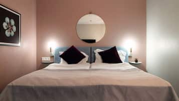 A neatly made bed with a large round mirror above it, two bedside tables with lamps, and a framed artwork on the wall.