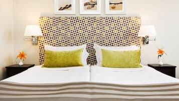 A hotel room with a patterned headboard, two bedside tables with lamps, and a bed with striped bedding.