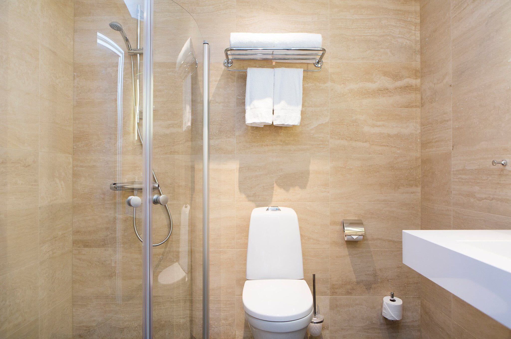 Une salle de bain moderne avec une douche à l’italienne en verre, des toilettes blanches et une grande baignoire blanche.