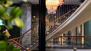 A modern interior with a staircase, metal railings, and a chandelier. - Elite Palace Hotel & Spa (Stockholm)