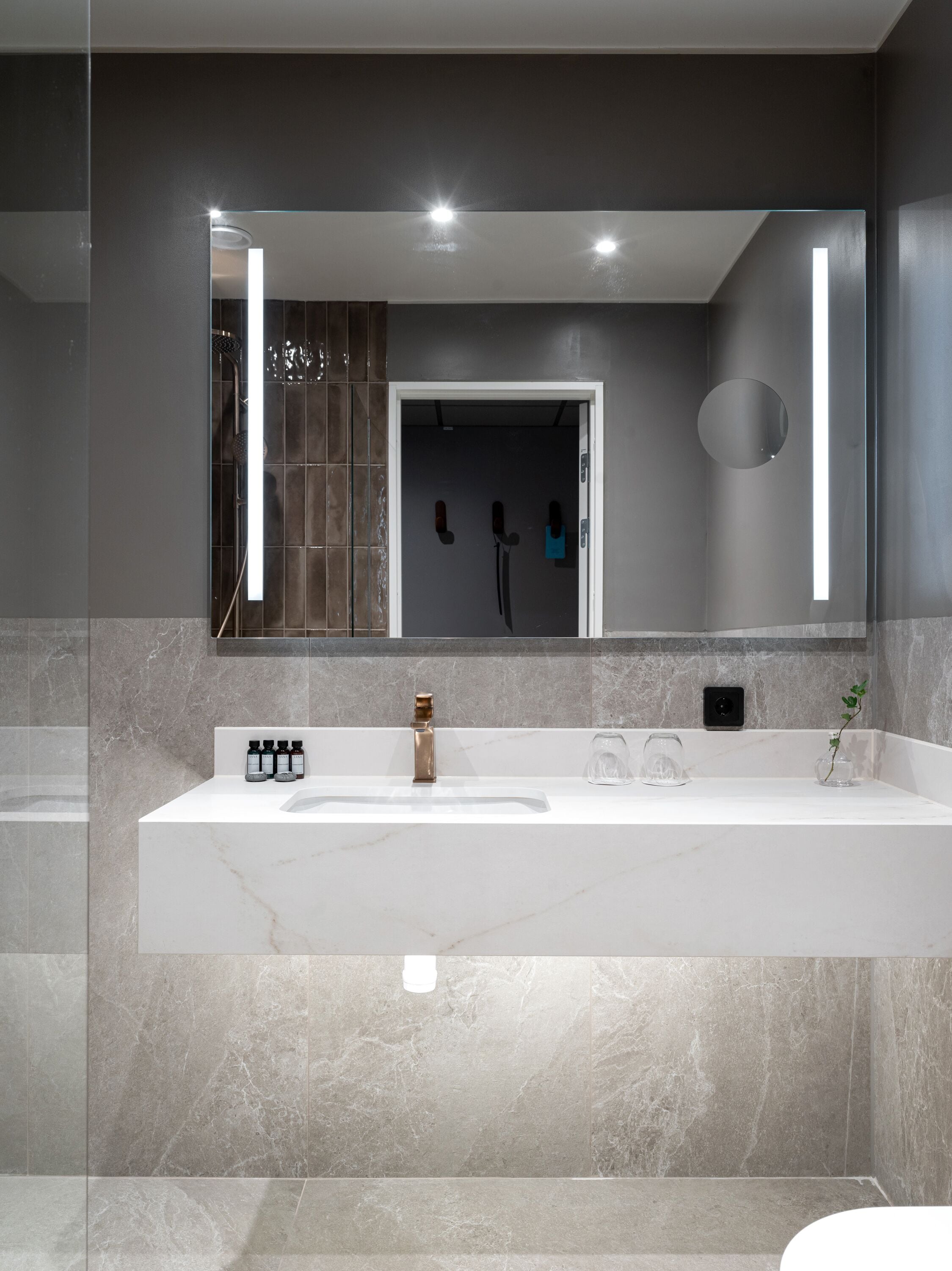 Un baño moderno con un espejo grande, un lavabo blanco y una zona de ducha.