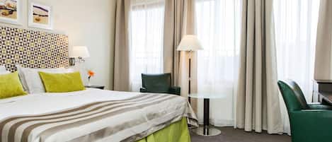 Una habitación de hotel con cama, escritorio, silla y lámpara.