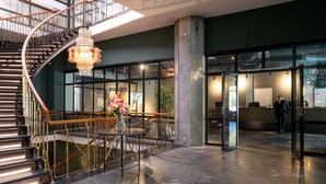 A modern lobby with a spiral staircase, a chandelier, and a seating area with a vase of flowers. - Elite Palace Hotel & Spa (Stockholm)