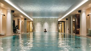A large indoor swimming pool with a person in the center, surrounded by walls and doors. - Elite Palace Hotel & Spa (Stockholm)