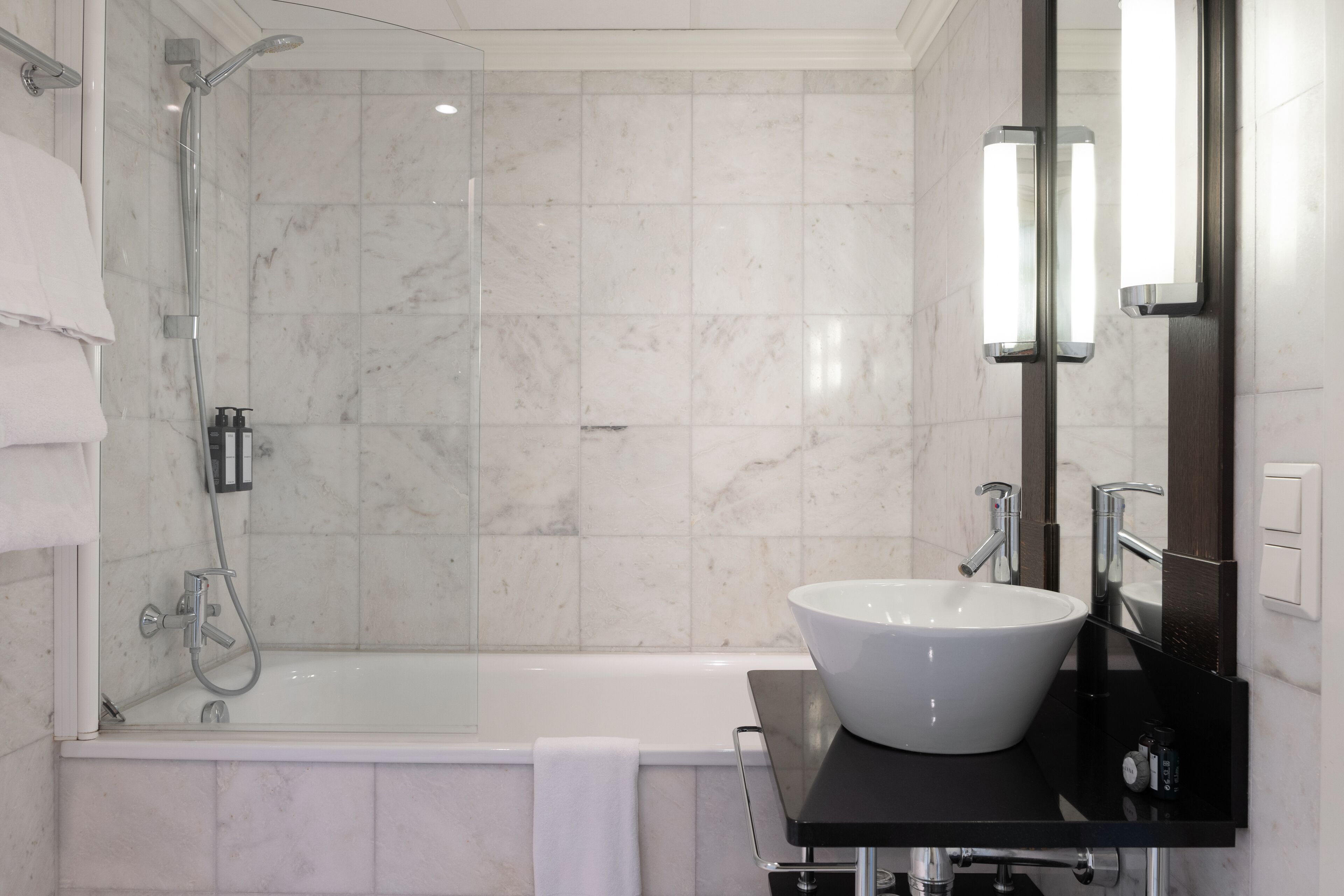 Un baño moderno con bañera, un lavabo grande de color blanco y una zona de ducha con mampara de vidrio.