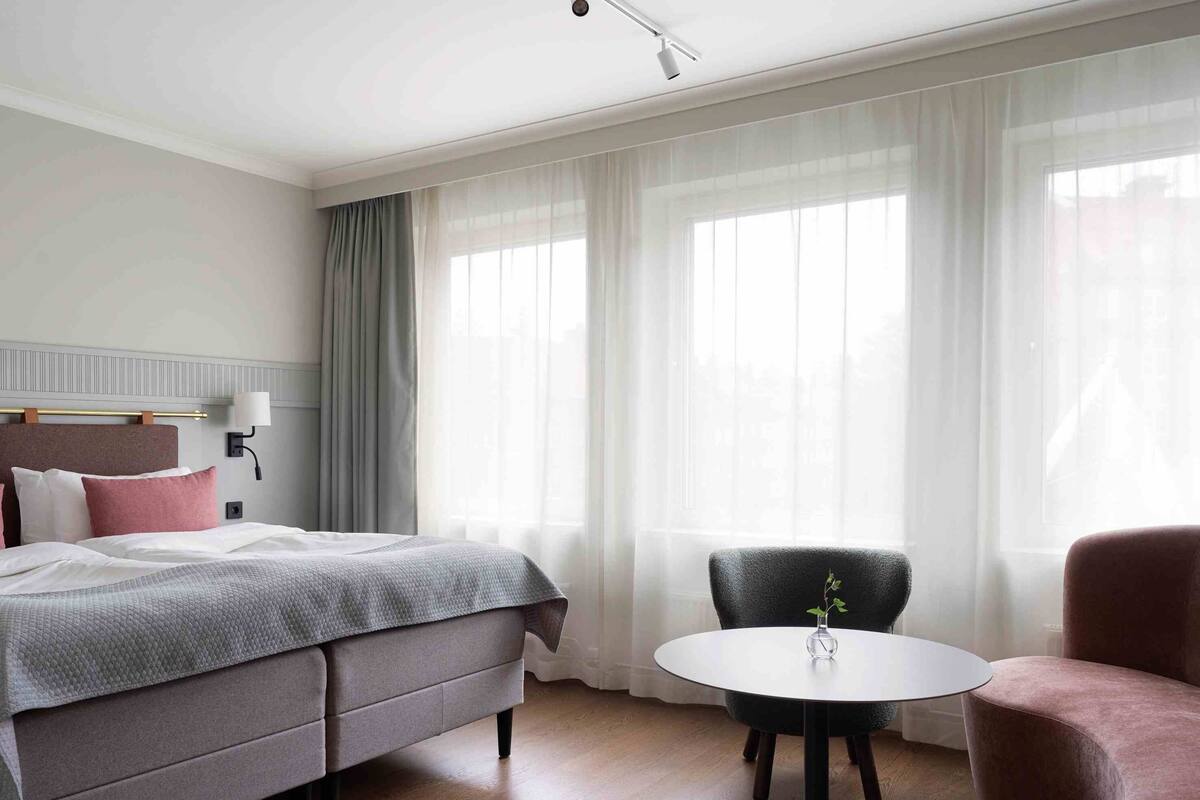 Une chambre d’hôtel avec un lit, une table ronde et deux chaises.