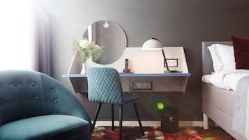 A hotel room with a desk, chair, bed, and a large mirror.