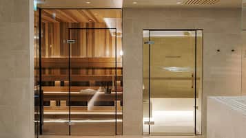 A modern sauna room with wooden paneling and a glass door labeled "FINNISH SAUNA".