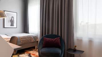 Habitación de hotel con cama, una silla, una mesita y un cuadro en la pared.