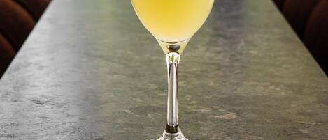 A martini glass with a lime wedge on a metal table in an outdoor seating area.