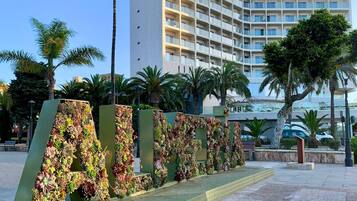 Un hotel con diseño moderno, que presenta un edificio grande con varios balcones y un letrero que indica que es un hotel.