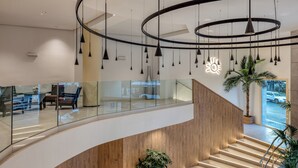 Un intérieur moderne avec un escalier à volutes, des rampes en verre et des luminaires suspendus.