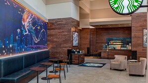 A modern Starbucks with a large digital art display, seating areas, and a bar. - Little Rock Marriott (Little Rock)