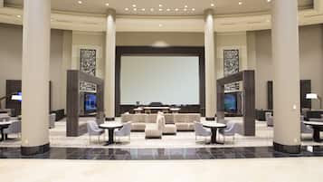 A spacious lobby with a large seating area, a central screen, and multiple televisions.