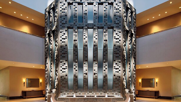 A lobby with a central seating area, a large wall with a geometric pattern, and a reception desk. - Little Rock Marriott (Little Rock)