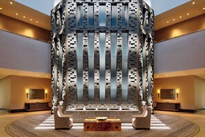 A lobby with a central seating area, a large wall with a geometric pattern, and a reception desk. - Little Rock Marriott (Little Rock)
