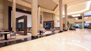 A spacious lobby with high ceilings, large pillars, and a central seating area with tables and chairs. - Little Rock Marriott (Little Rock)